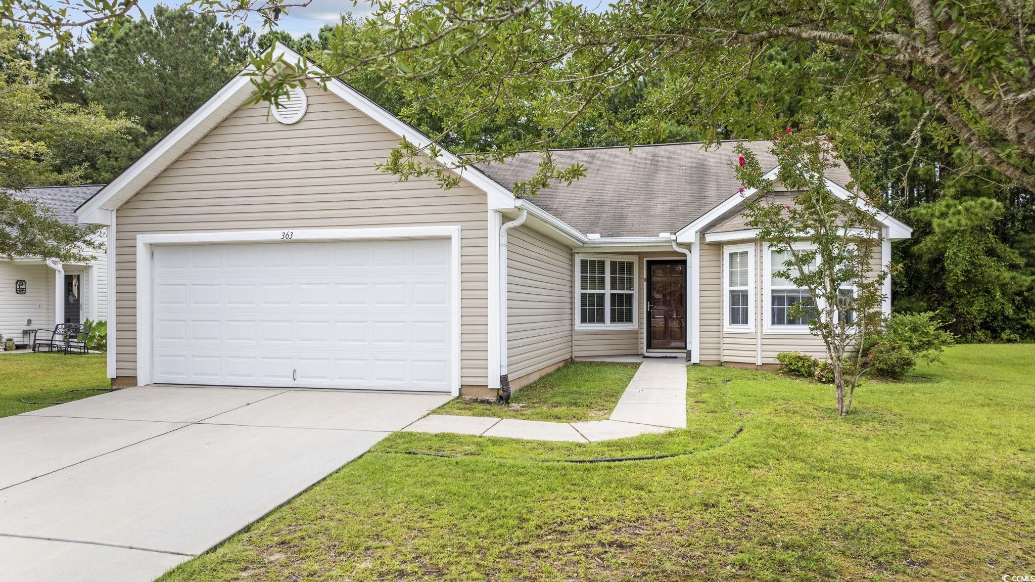 Ranch-style house featuring a front yard and a gar