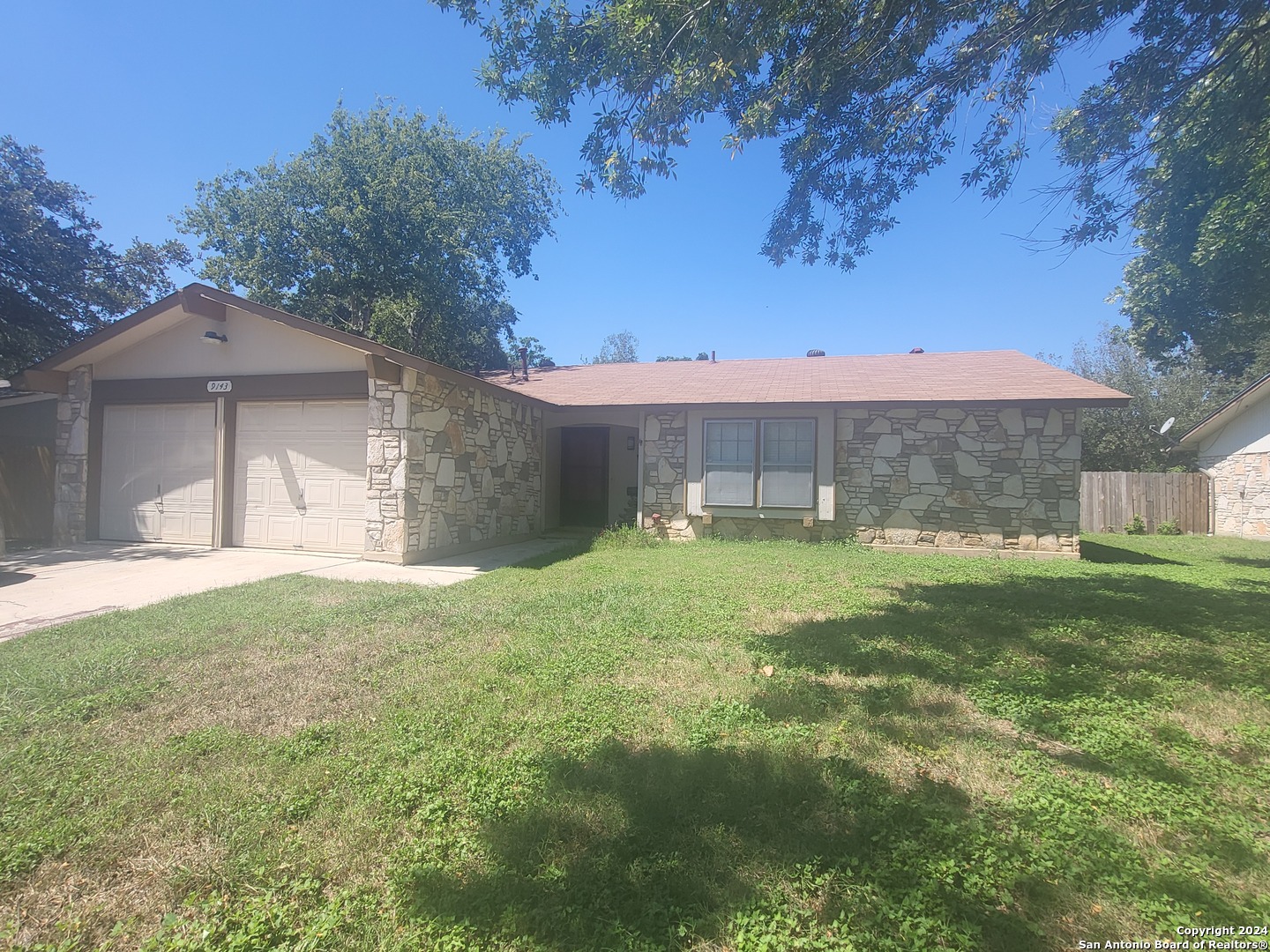 a view of a house with a yard and a large tree