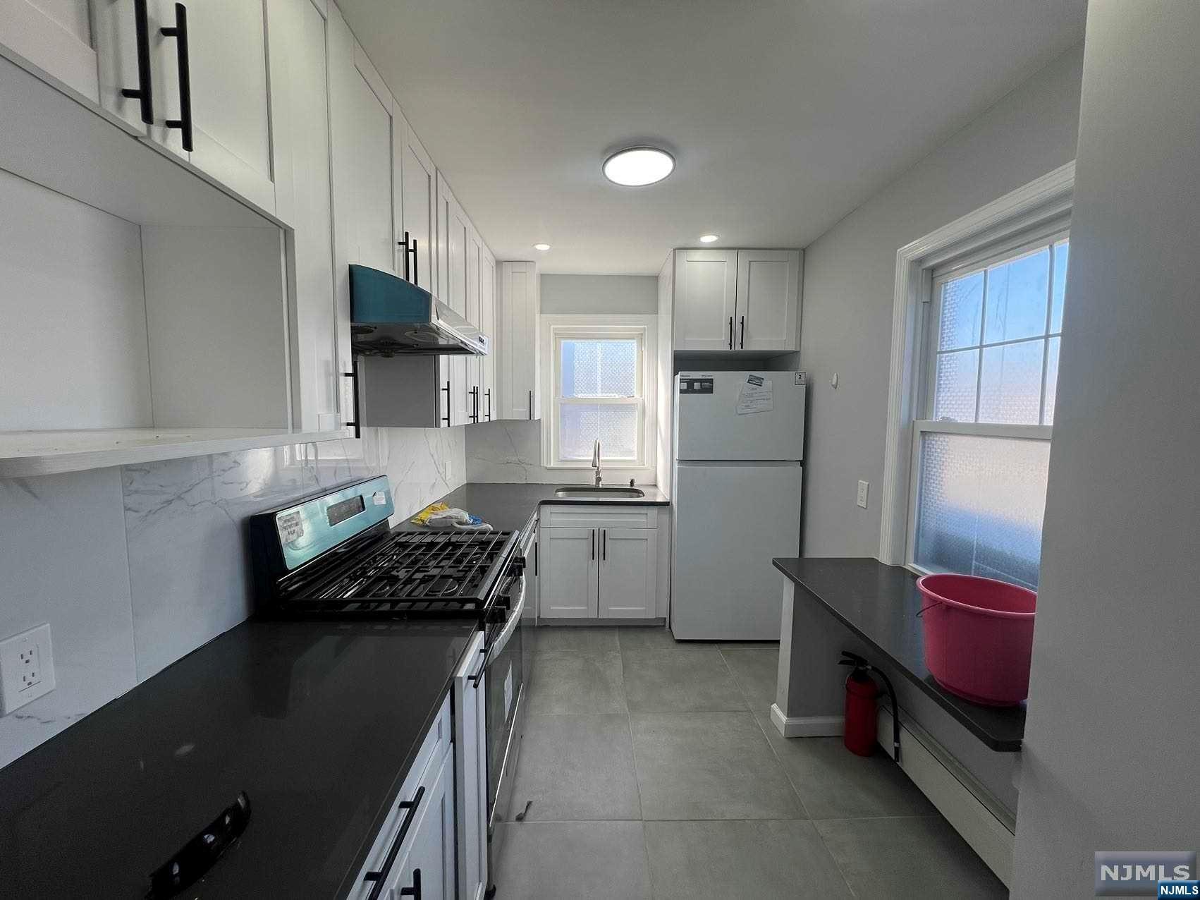 a kitchen with granite countertop a refrigerator stove top oven and sink