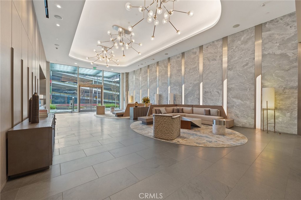 a living room with couches a chandelier and kitchen view