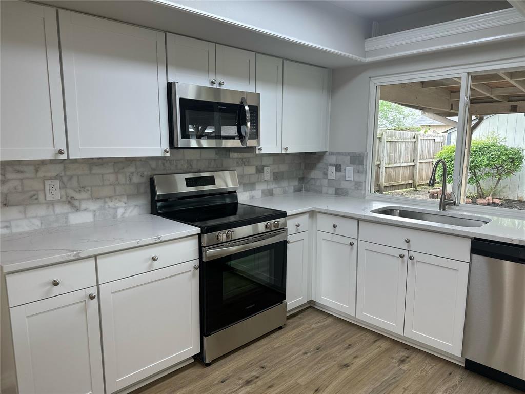 a kitchen with white cabinets appliances and a window