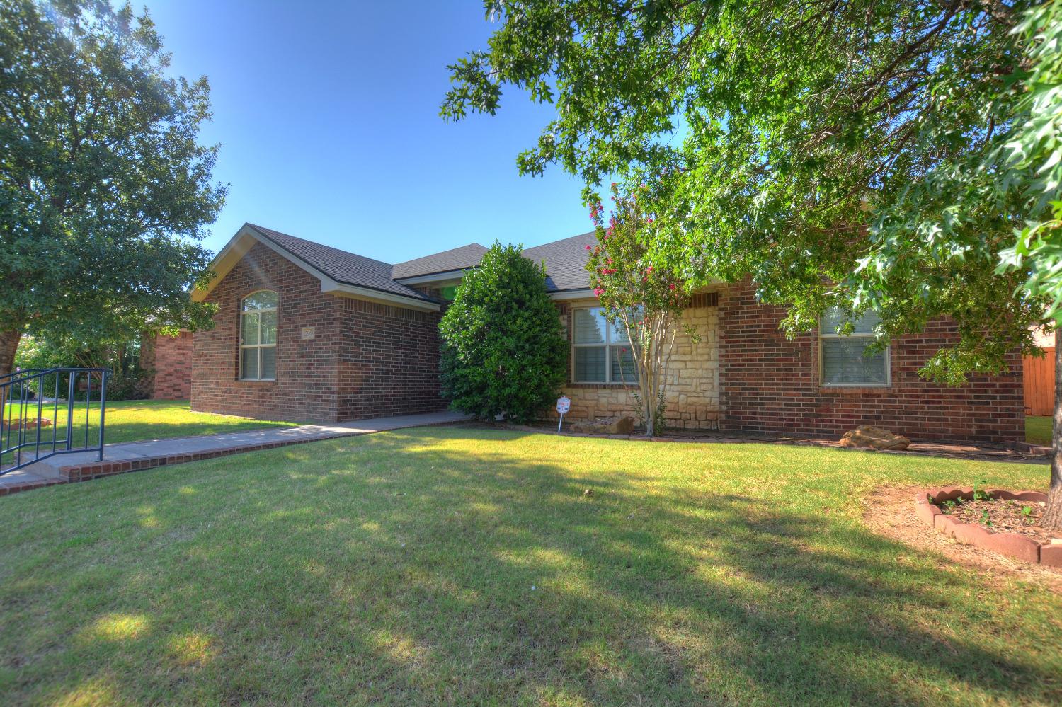 a view of a house with a yard and large tree