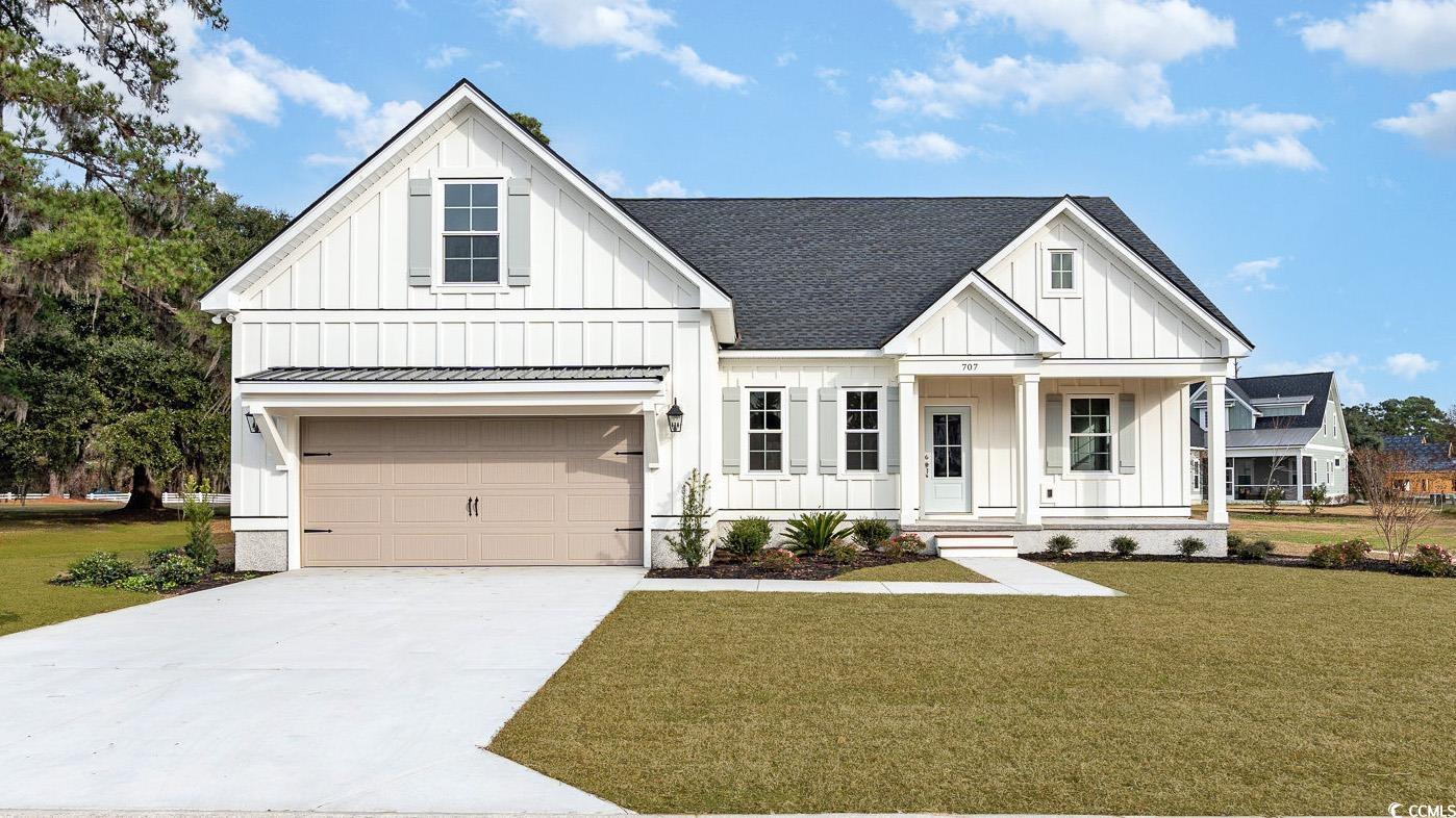 Modern farmhouse style home with a front yard, a g