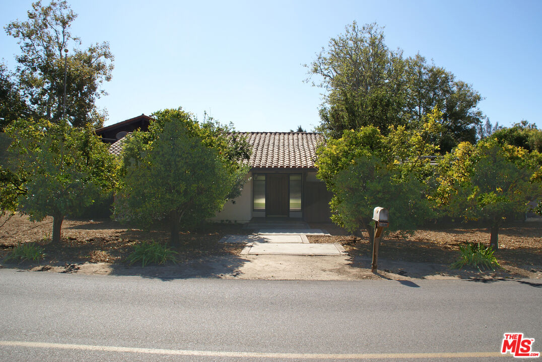 a front view of a house with a yard and tree s