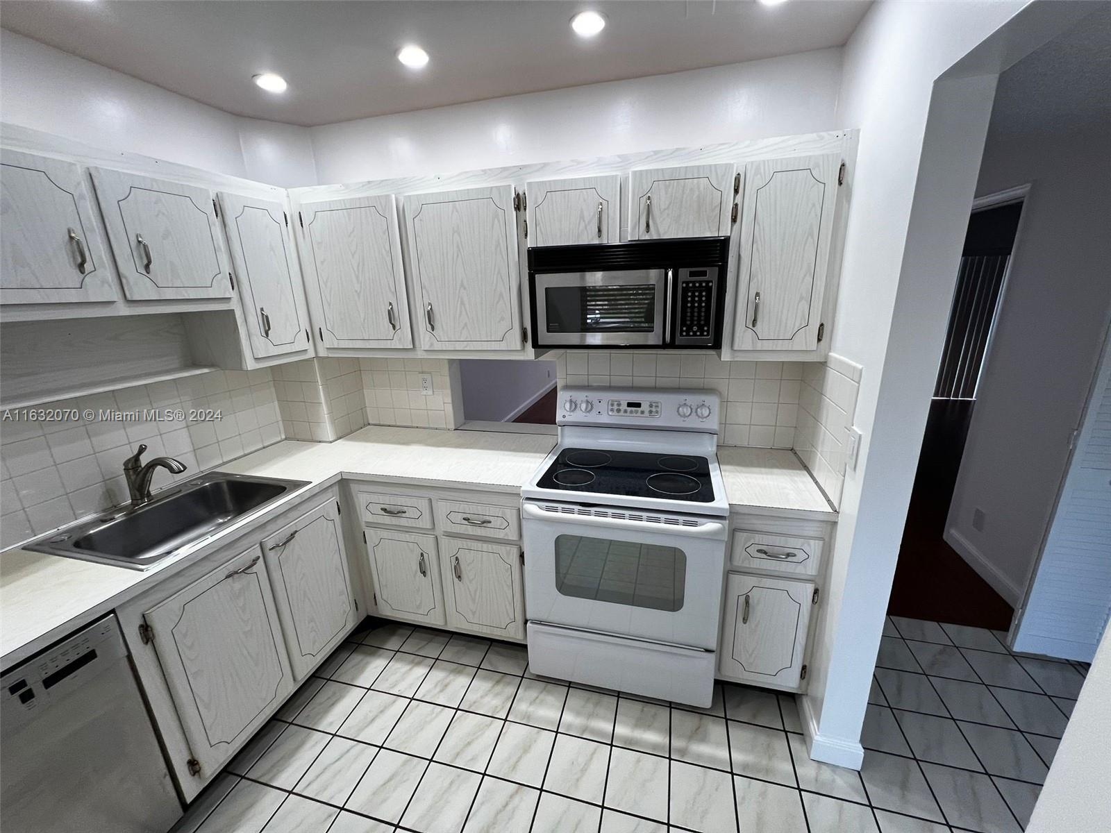 a kitchen with white cabinets stainless steel appliances and sink