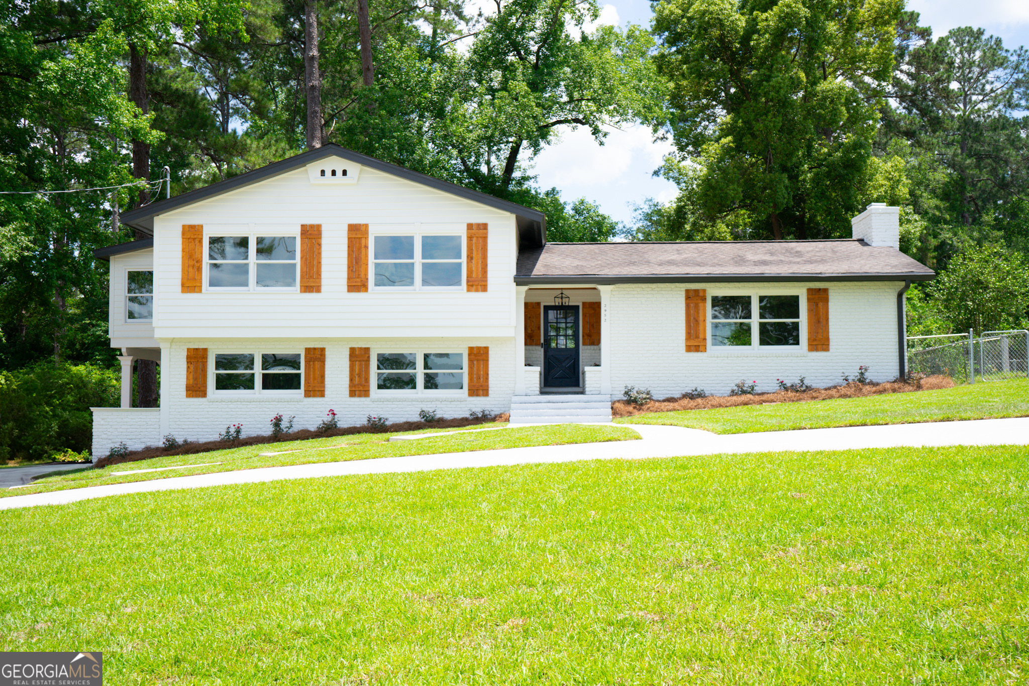 a view of a house with a big yard and large trees