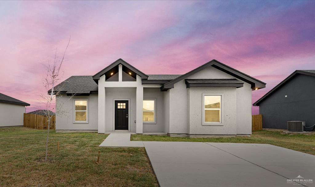 View of front of home featuring a patio, a yard, and central AC