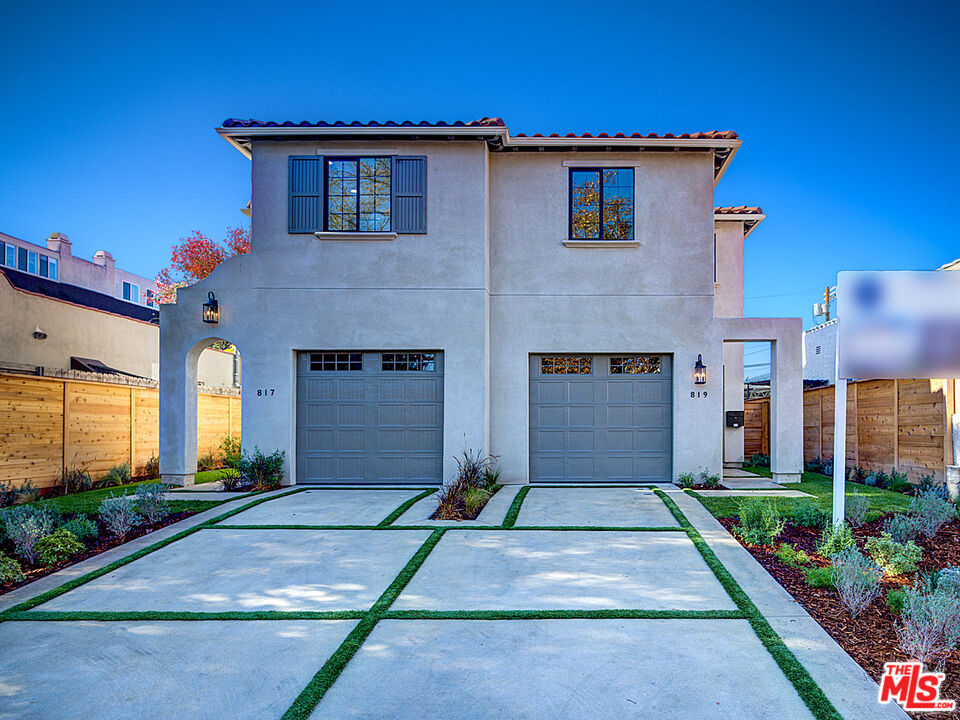 a front view of a house with a yard and potted plants