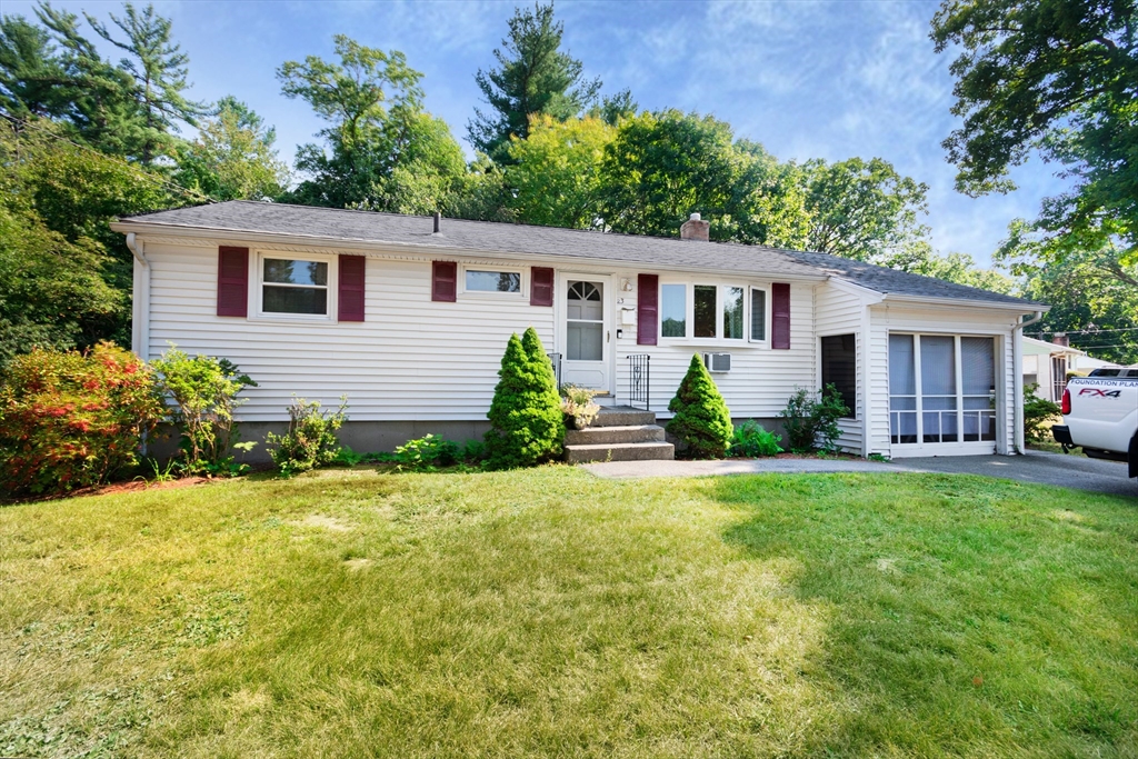 a front view of house with yard and trees in the background