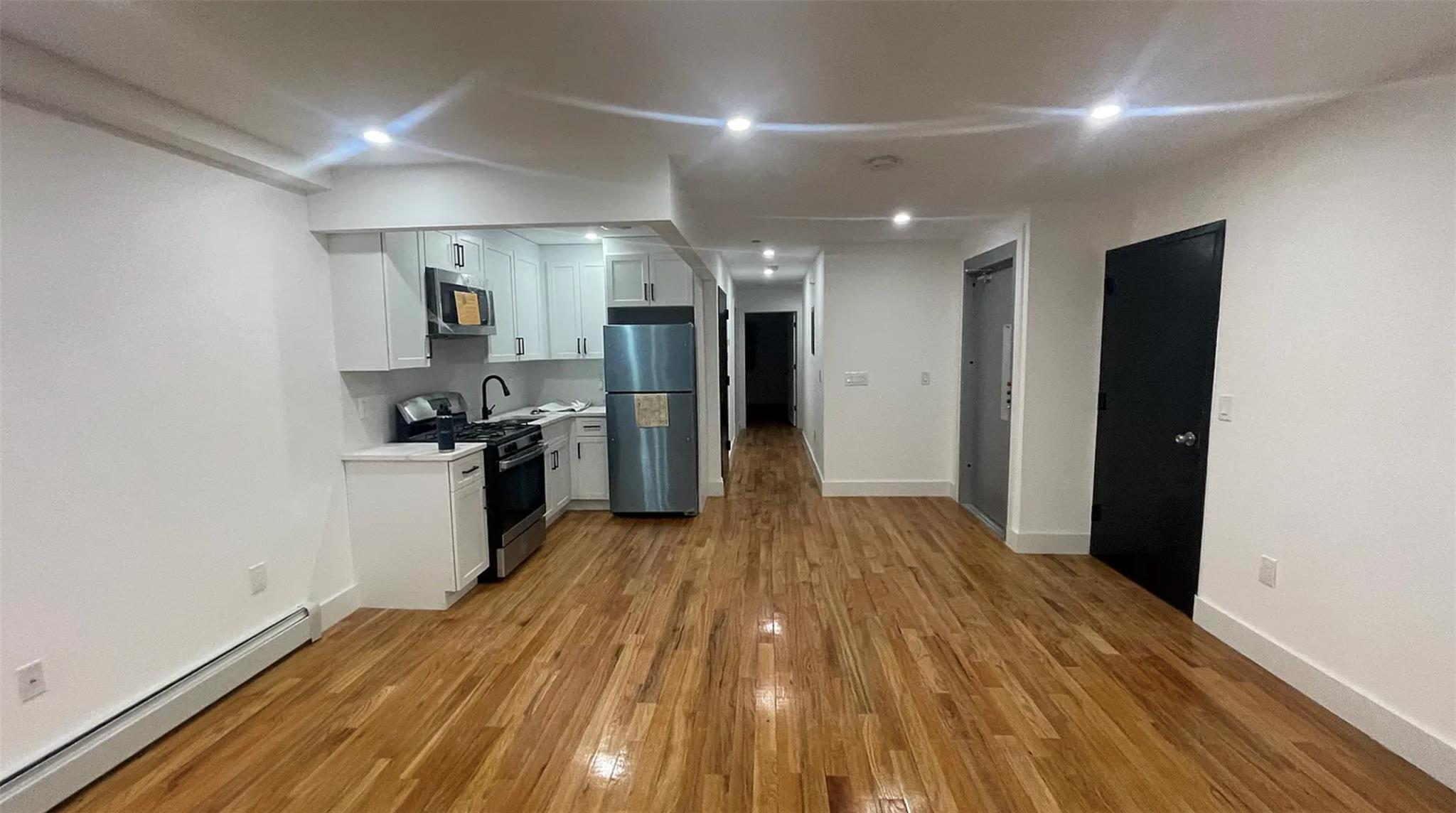 a view of a kitchen with refrigerator and wooden floor