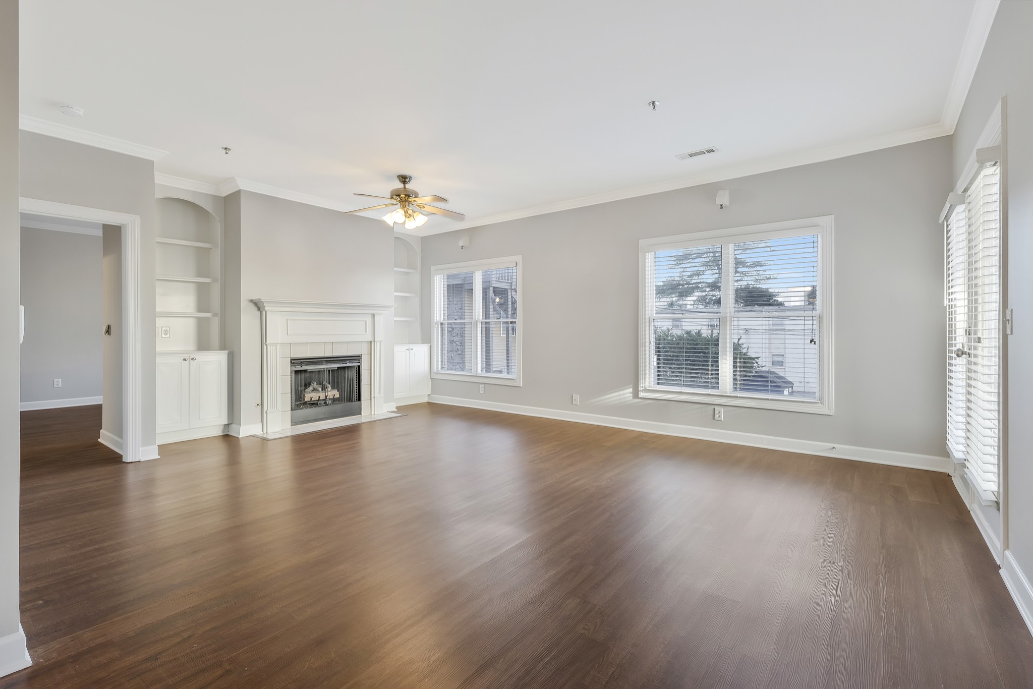 an empty room with windows a fireplace and wooden floor