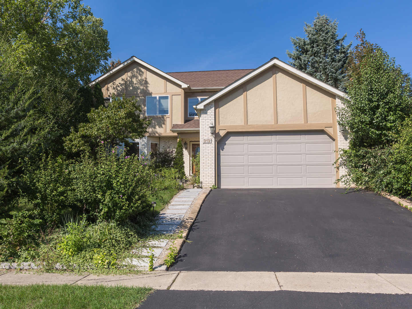 a view of house with garage and plants