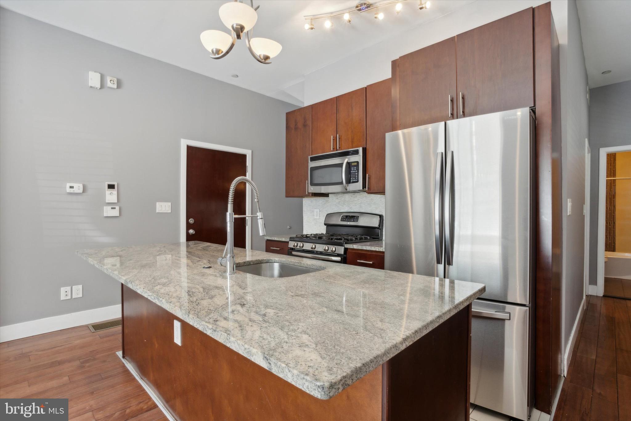 a kitchen with stainless steel appliances granite countertop a sink refrigerator and microwave