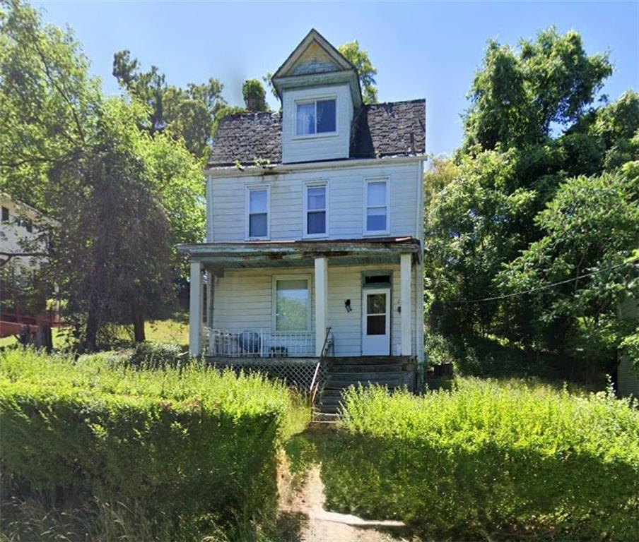 a view of a brick house with a big yard and large trees