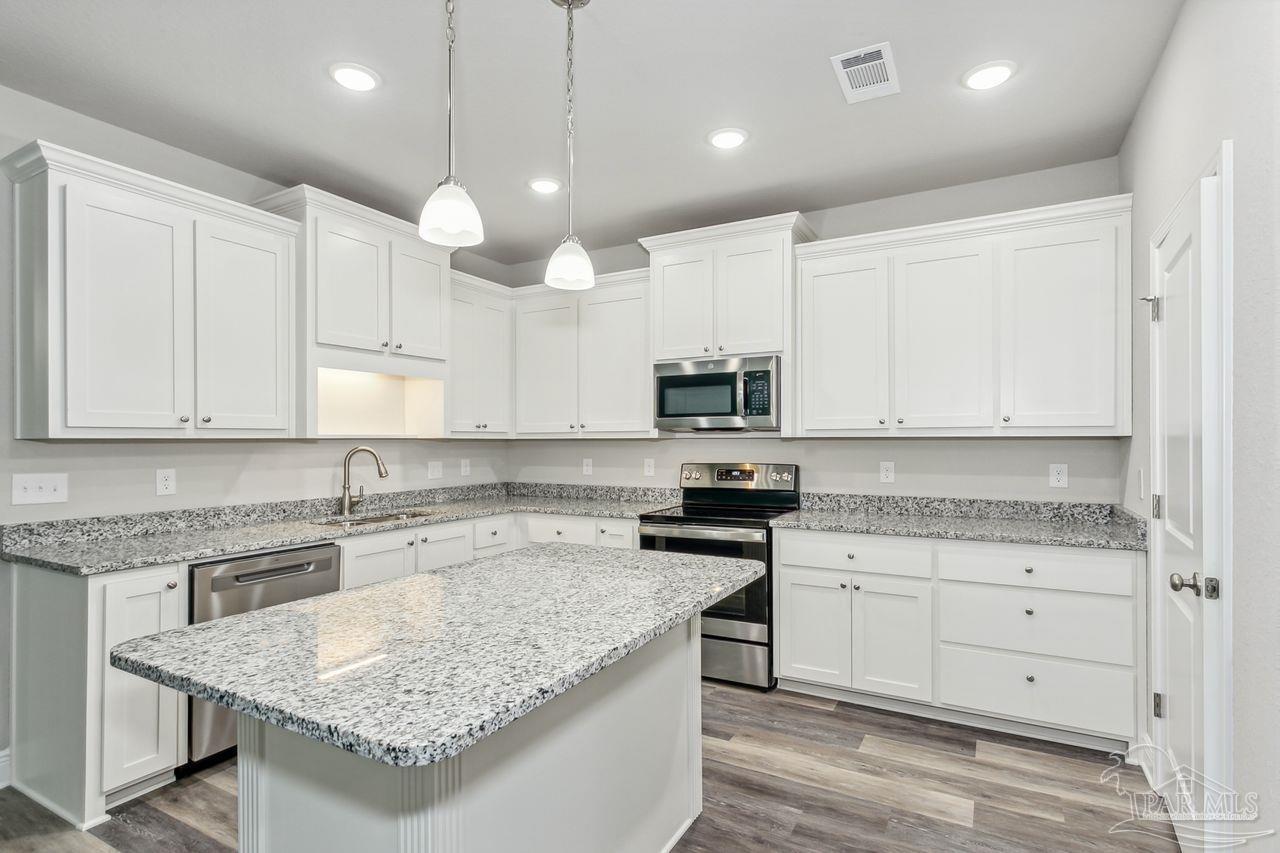 a kitchen with stainless steel appliances granite countertop a sink stove and cabinets