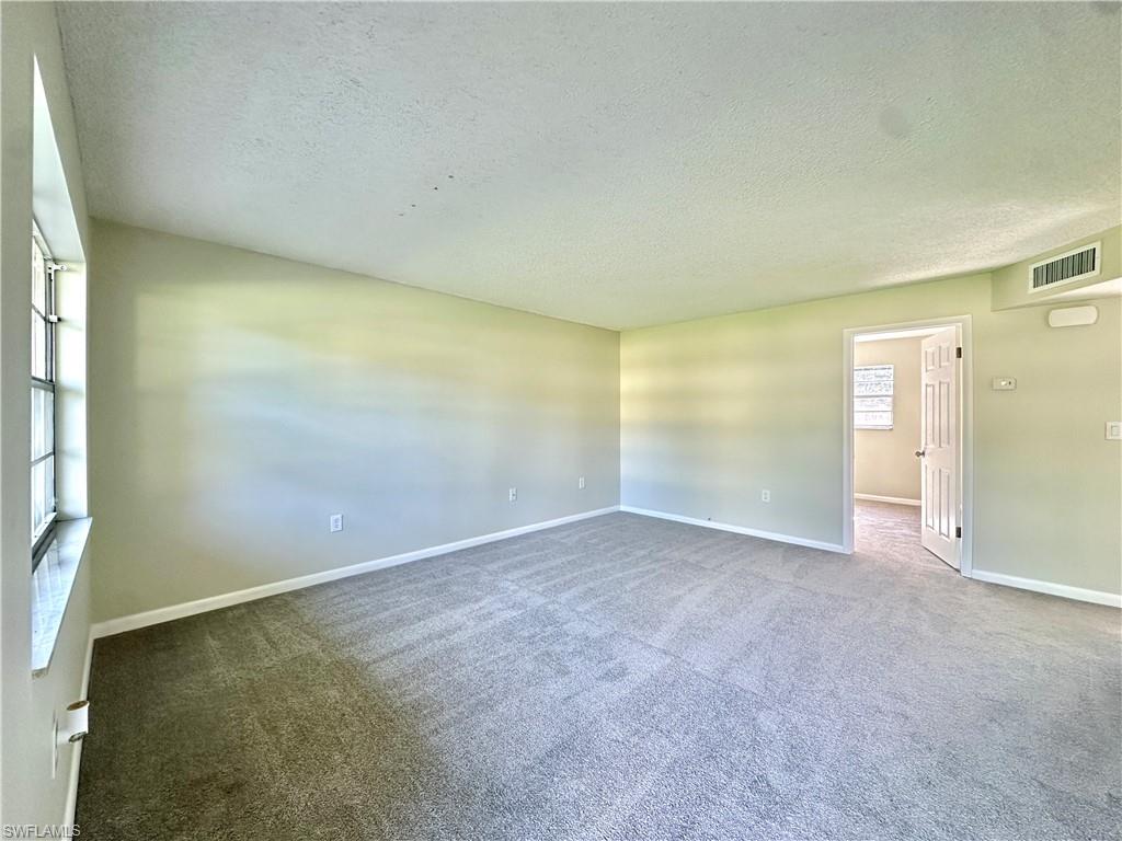 Carpeted empty room featuring a textured ceiling