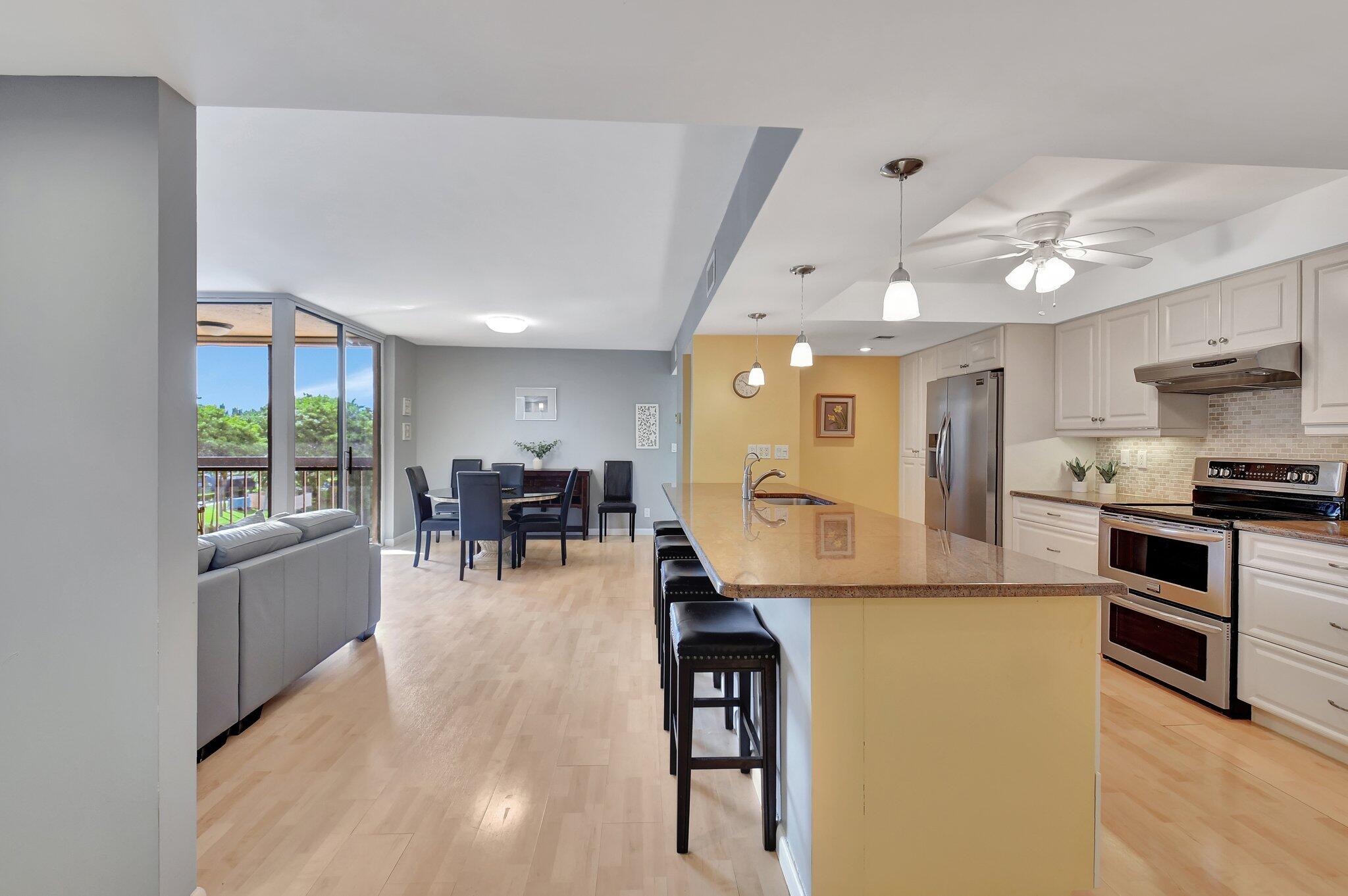 a kitchen with stainless steel appliances granite countertop a stove refrigerator and a view of living room