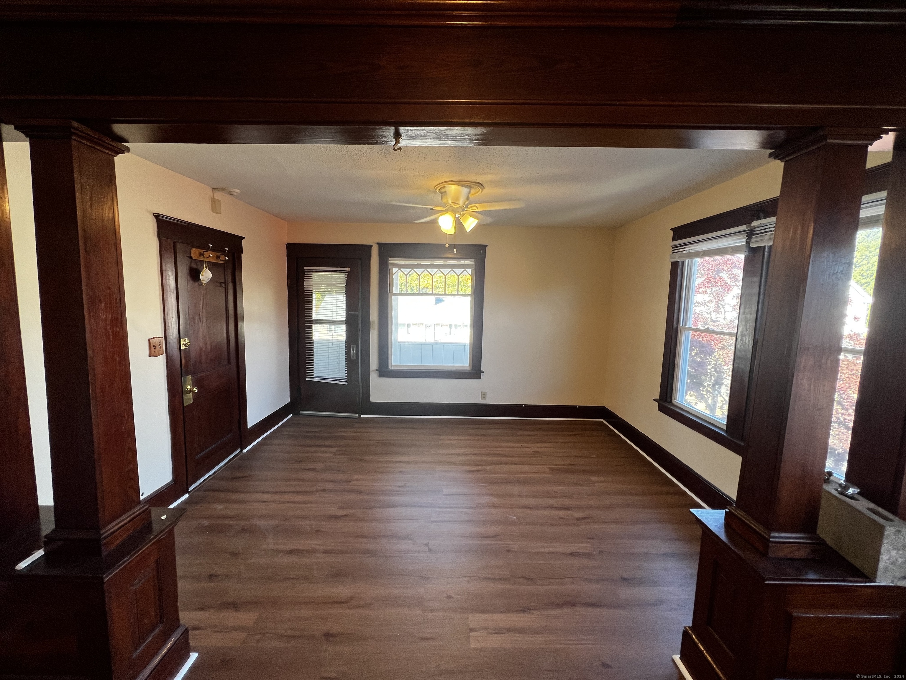 a view of an empty room with wooden floor and a window