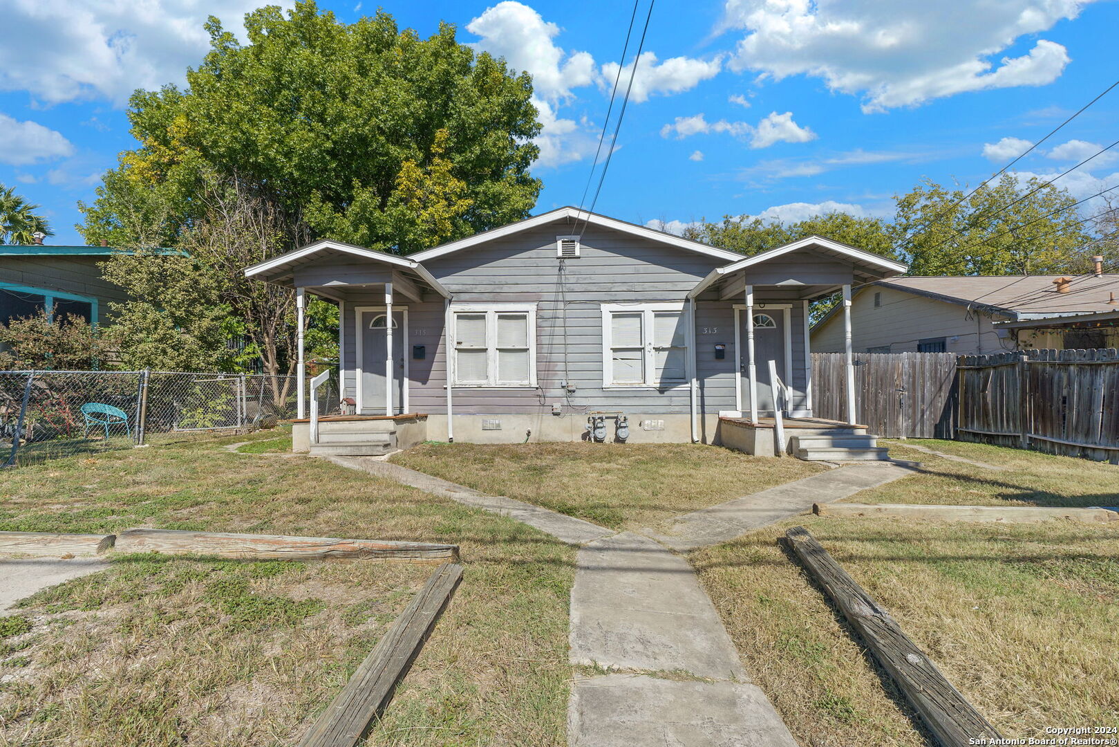 a view of a house with a yard and large tree