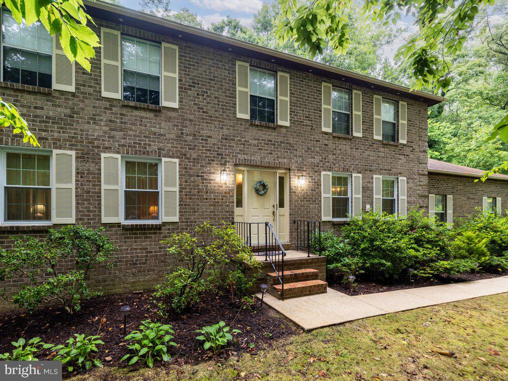 a view of a brick house with a yard potted plants and large tree