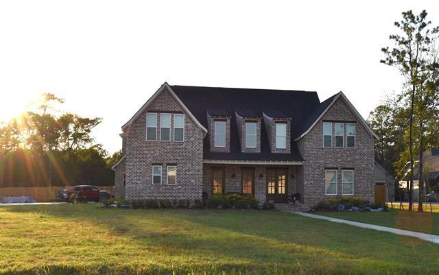 a view of a big house with a big yard and large trees