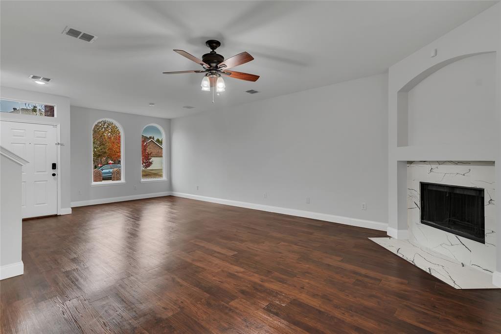 a view of an empty room with window and wooden floor