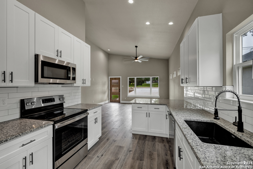 a kitchen with granite countertop a sink wooden floor and stainless steel appliances