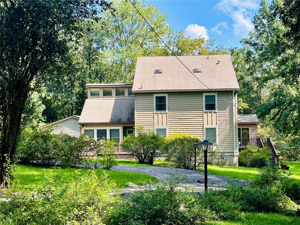 a brick house with a yard plants and large tree