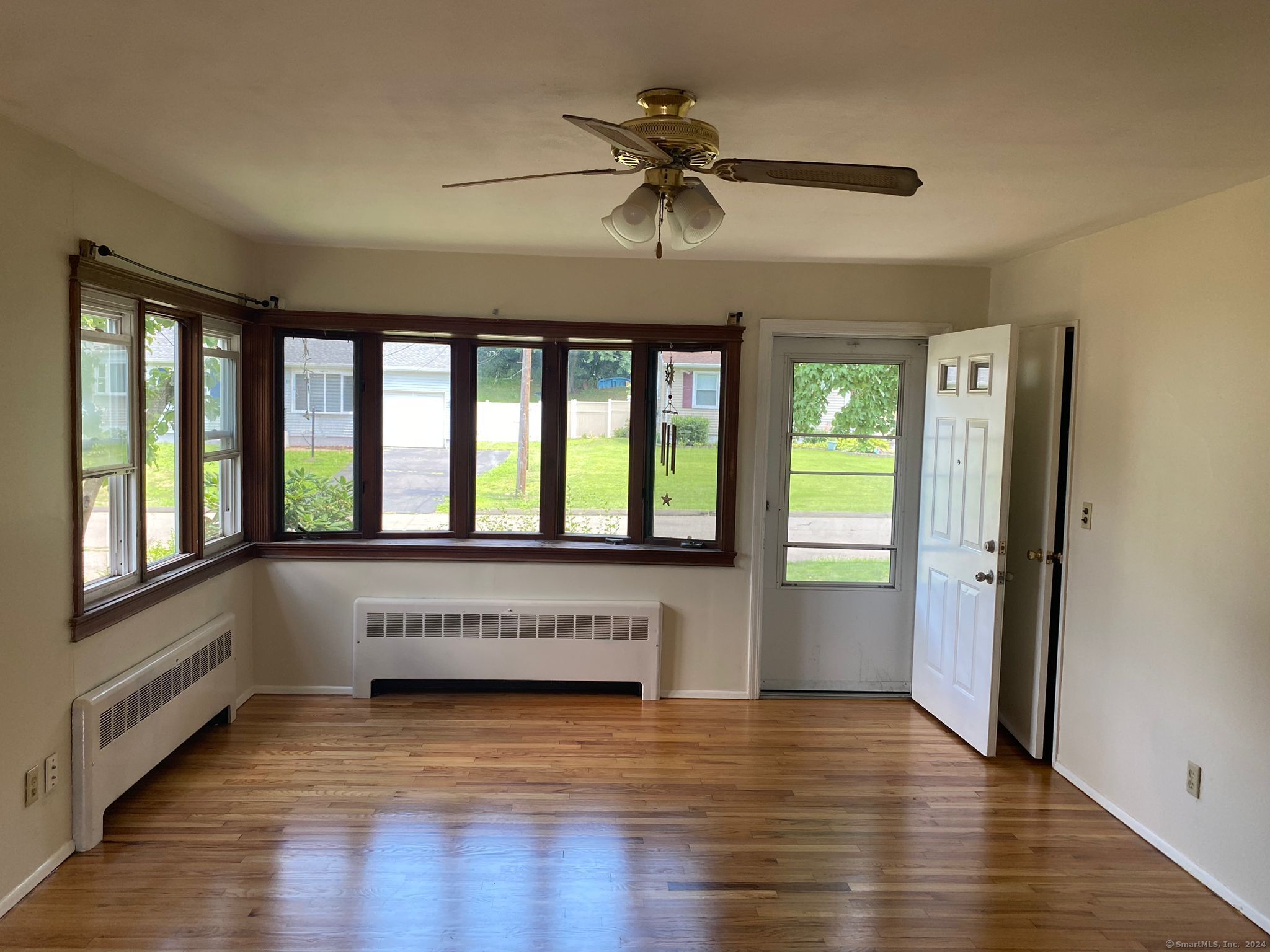 a view of an empty room with wooden floor and a window