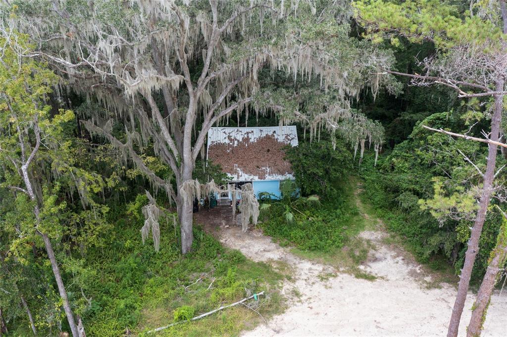 an aerial view of residential house with outdoor space and trees all around