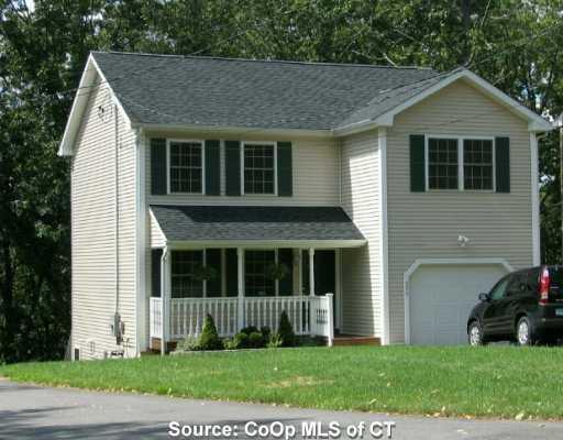 a view of a brick house with a large windows and a yard with plants and large trees