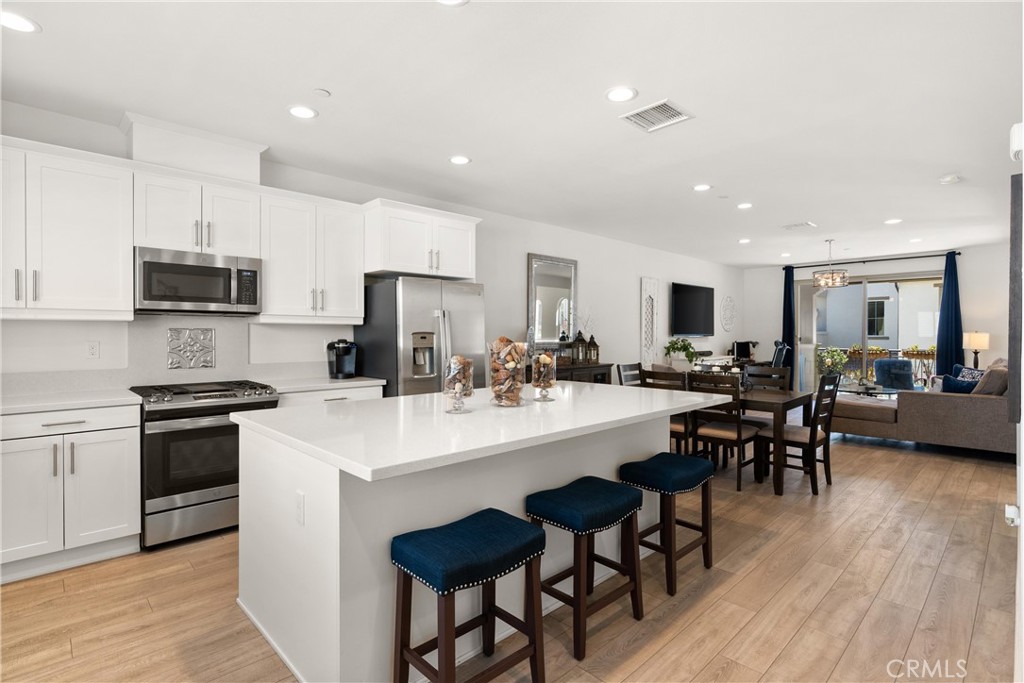 a kitchen with stainless steel appliances a table chairs refrigerator and microwave