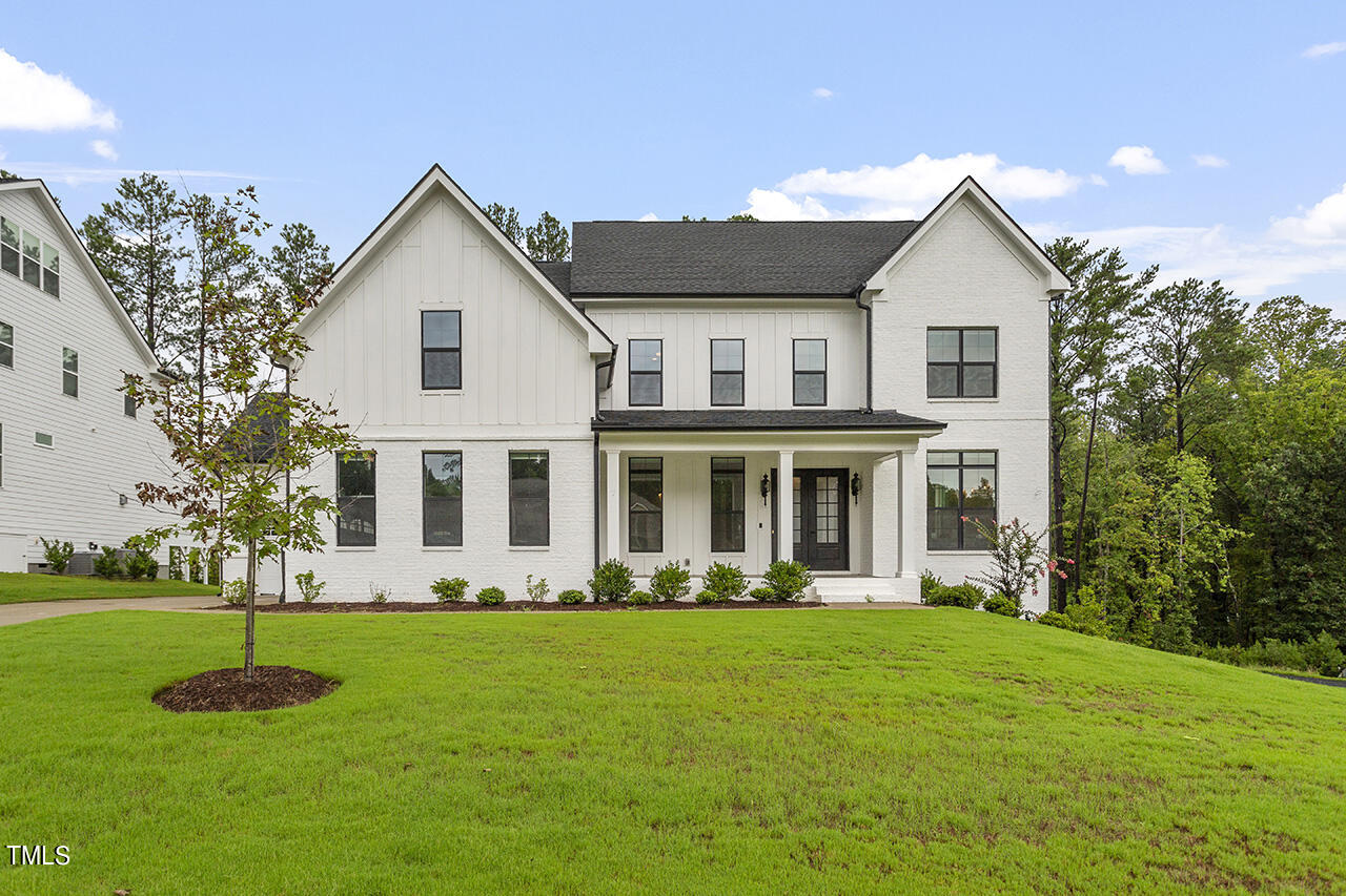 a front view of a house with a garden and trees