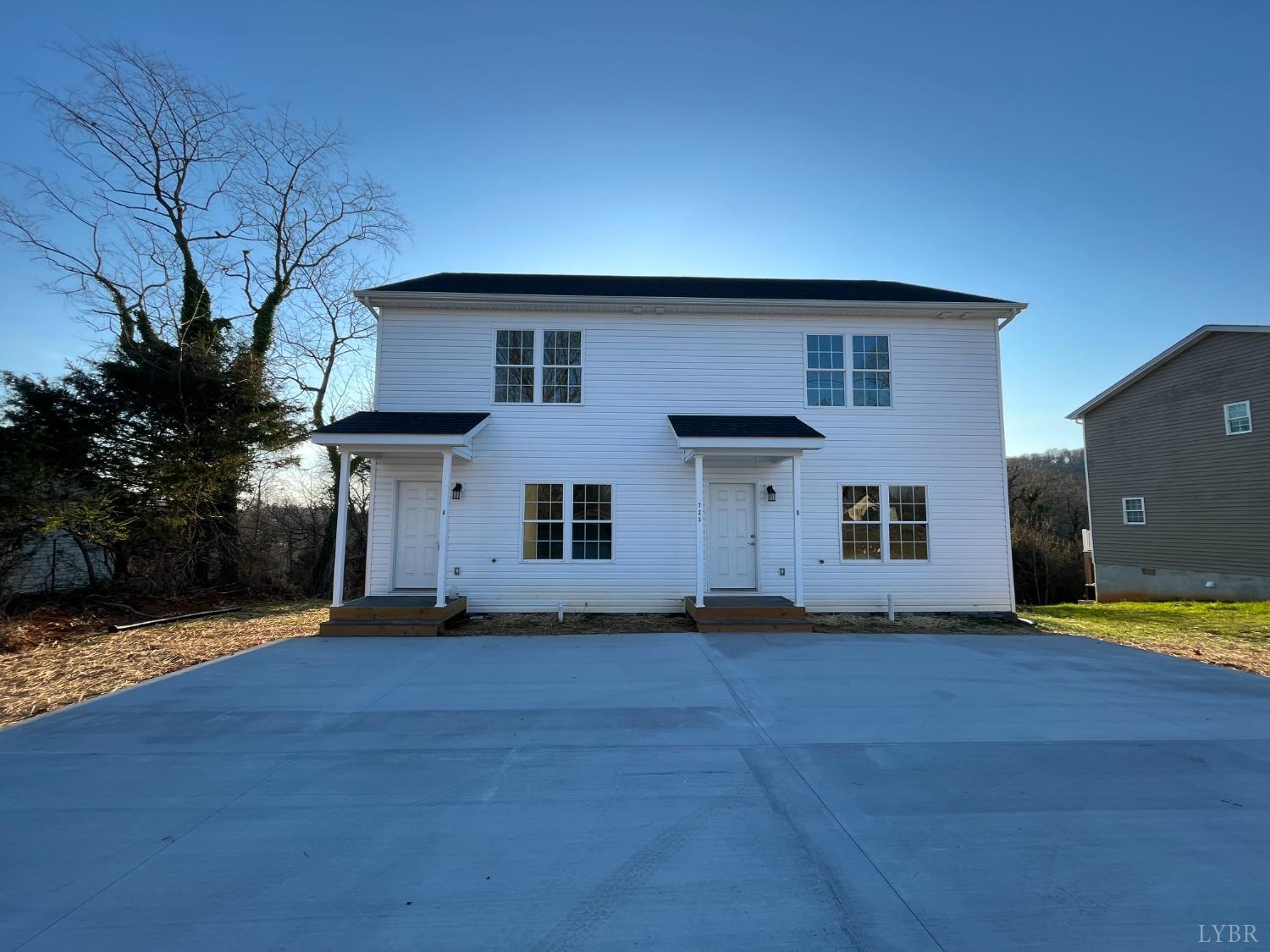 a front view of house with yard and trees in the background