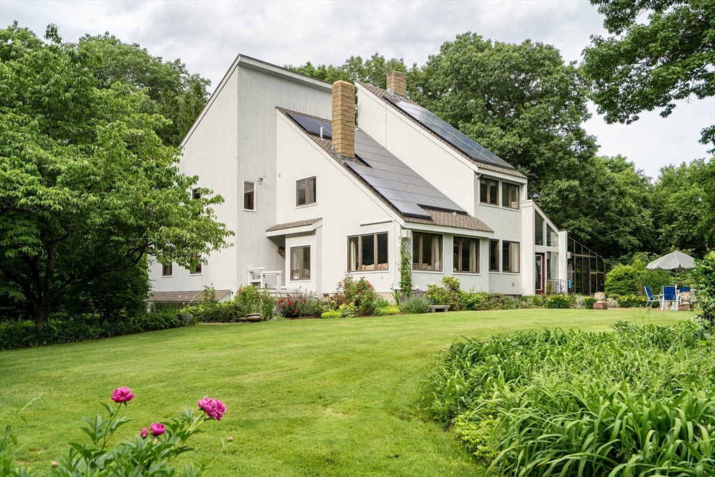 a white house with a small yard plants and trees all around