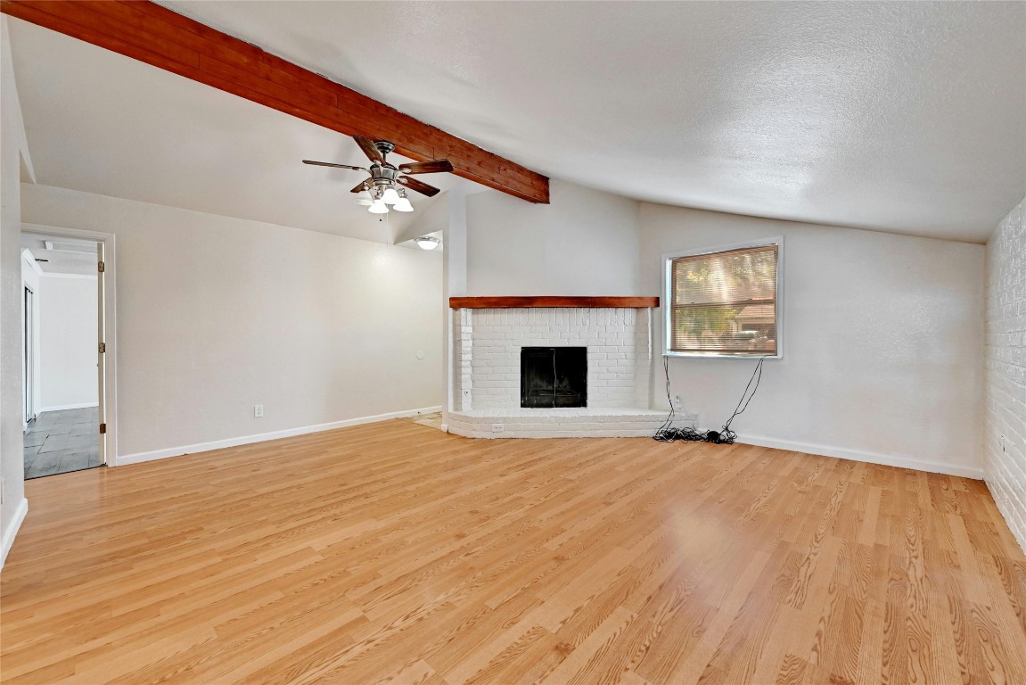 a view of empty room with fireplace and wooden floor