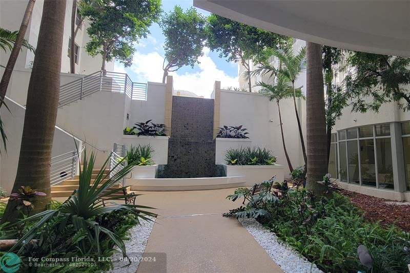 an front view of a house with a yard and fountain in middle