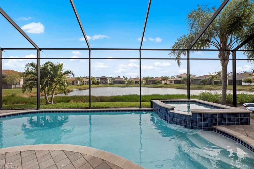 View of pool with a lanai, an in ground hot tub, and a water view