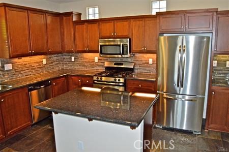 a kitchen with stainless steel appliances granite countertop a refrigerator a stove and a sink with wooden floor