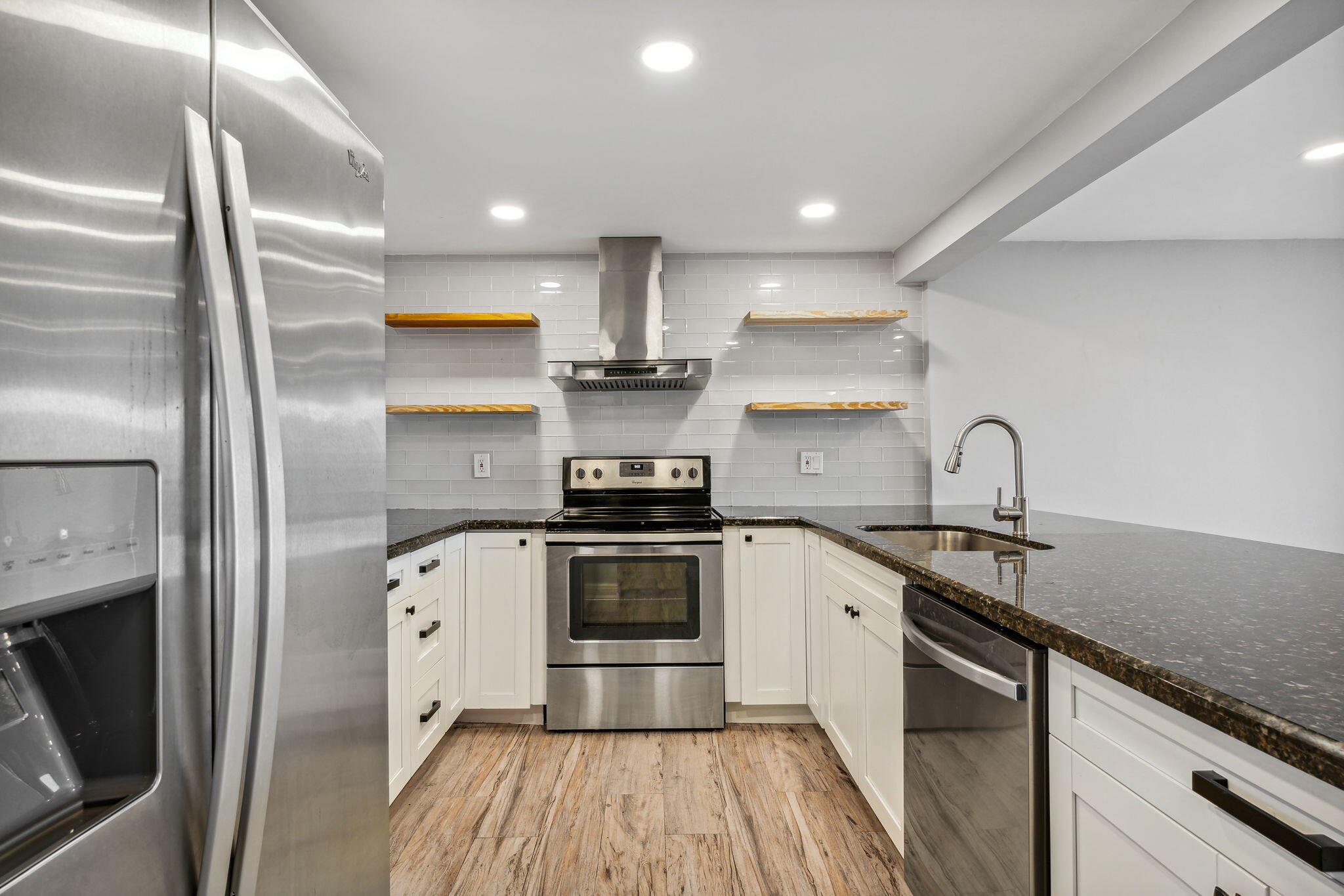 a kitchen with stainless steel appliances granite countertop a sink a stove and a refrigerator