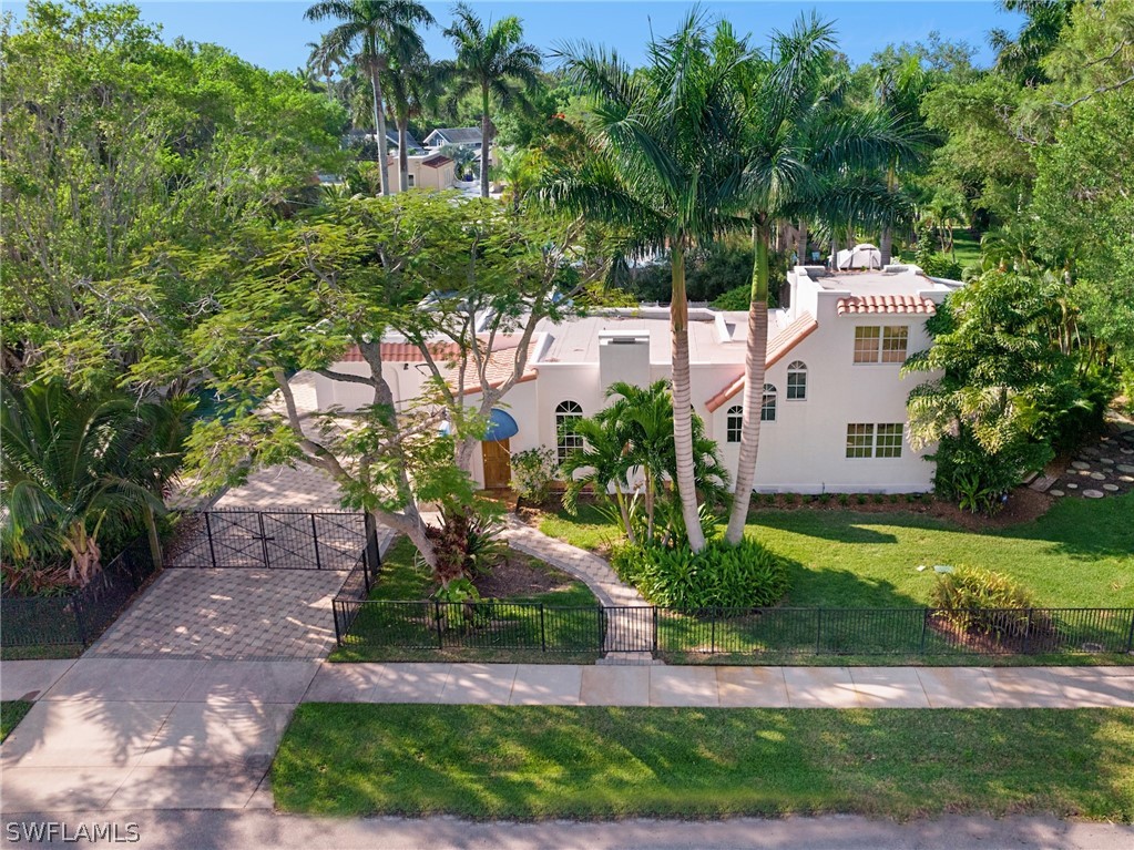 a view of a white house next to a yard with big trees