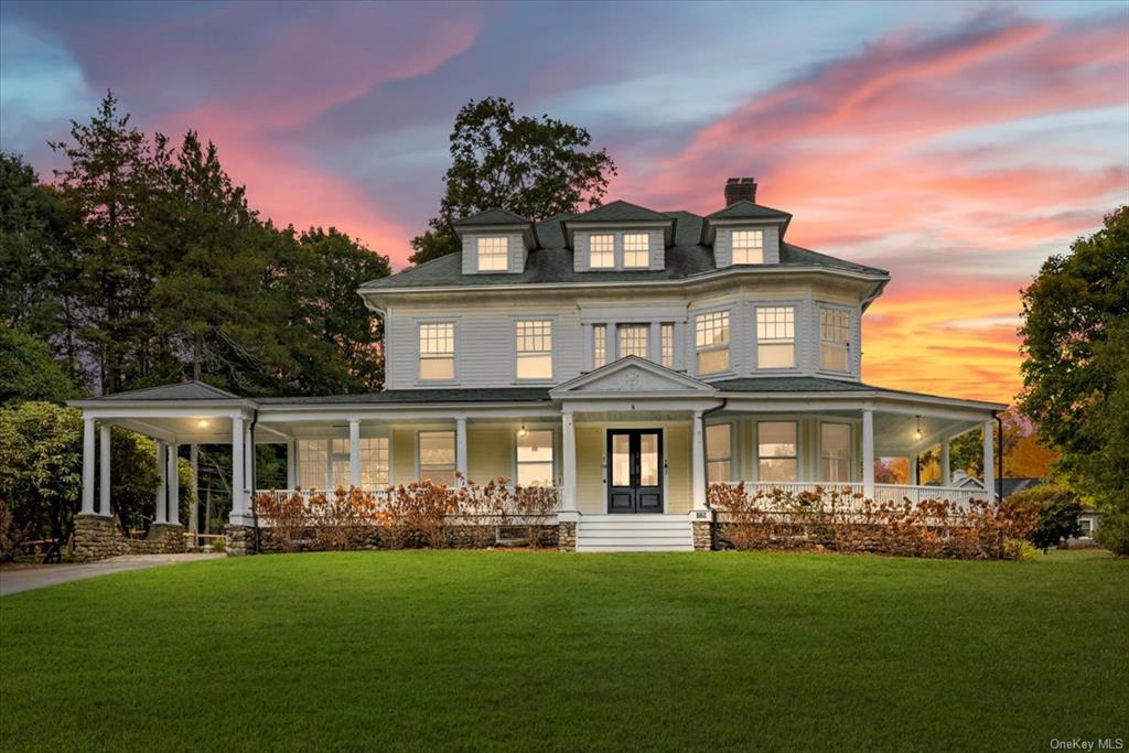 View of front facade featuring covered porch and a lawn