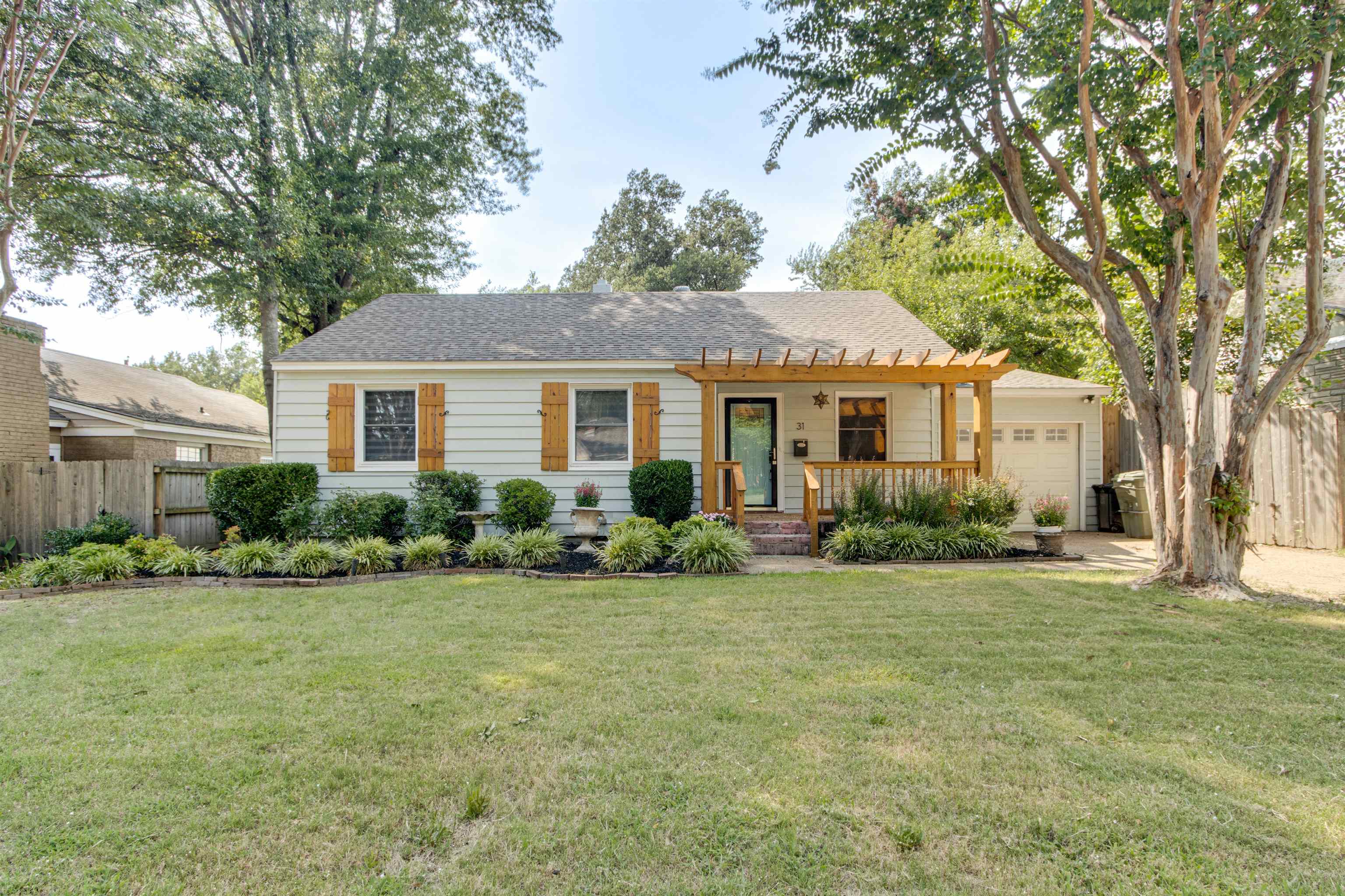 View of front of property featuring a garage, a pergola, and a front yard