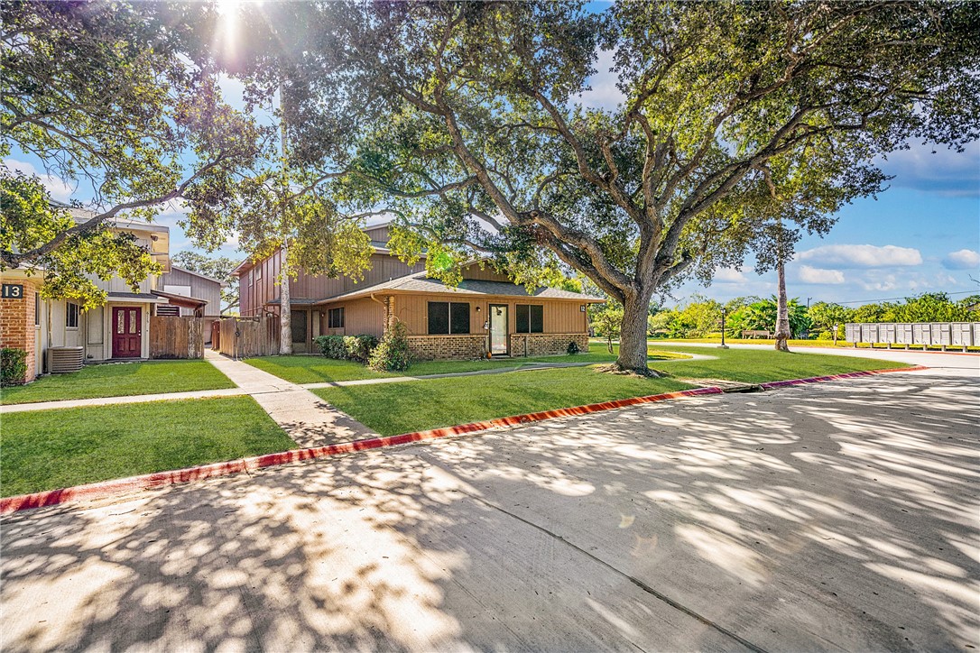 a view of a house with a yard and large trees