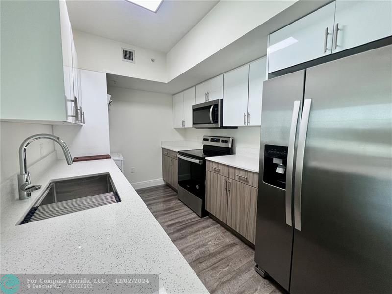 a kitchen with granite countertop a refrigerator and a sink