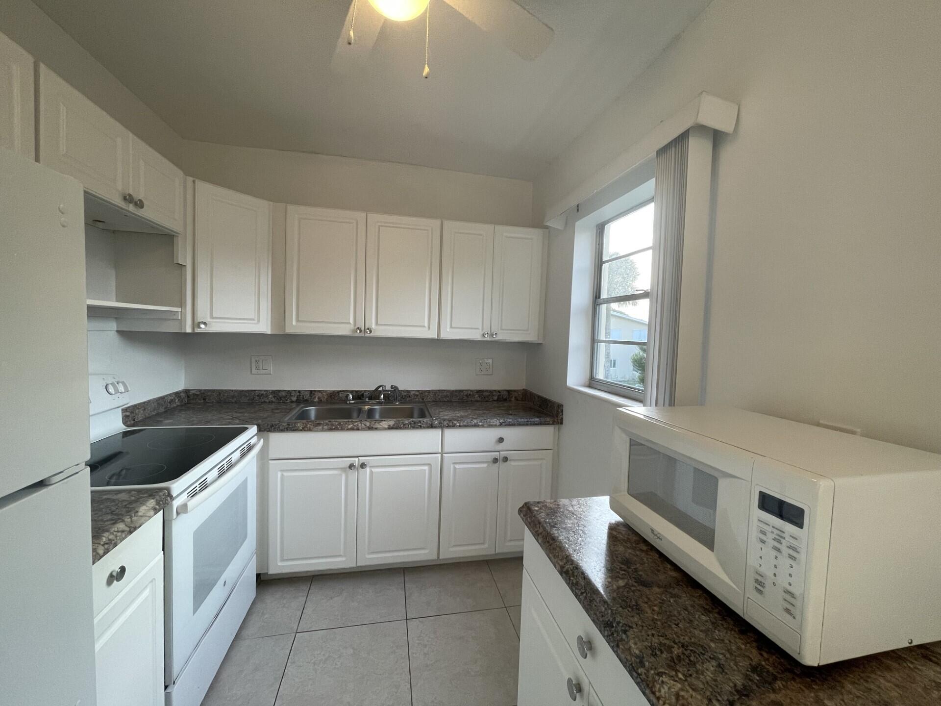 a kitchen with granite countertop white cabinets and white appliances