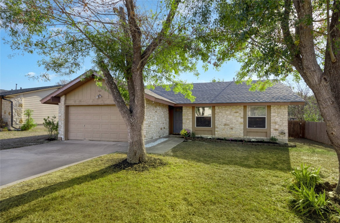 a view of a house with a yard and large tree