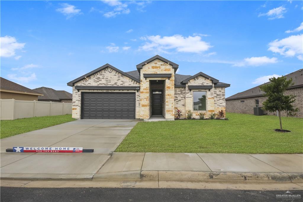 View of front facade featuring a front yard and a garage