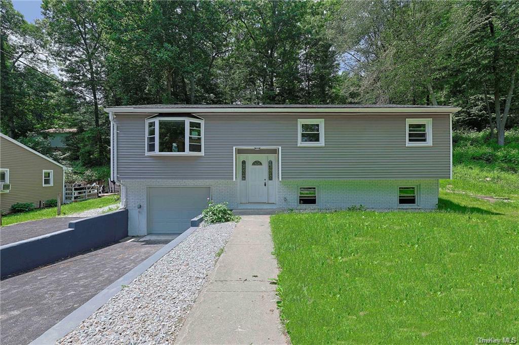 Split foyer home featuring a garage and a front lawn