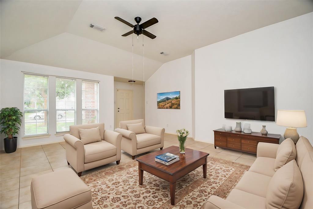 a living room with furniture a rug a window and a flat screen tv